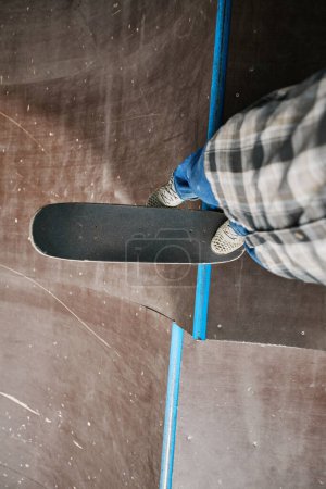 Téléchargez les photos : Vue de dessus minimale à un adolescent anonyme chevauchant du skateboard sur la rampe au parc de patinage et faisant des tours, copier l'espace - en image libre de droit