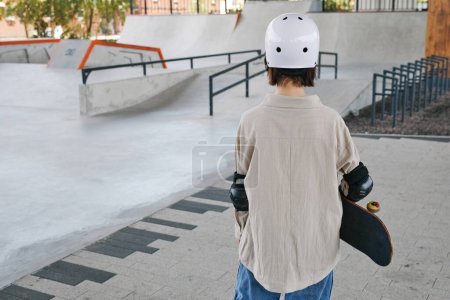 Photo for Minimal back view of young girl wearing protective guards and helmet in skating park outdoors, copy space - Royalty Free Image