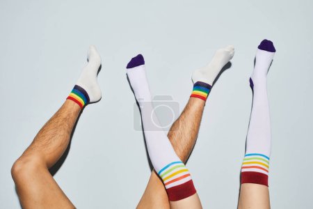 Photo for Vibrant shot of playful young couple wearing socks with rainbow symbols feet up against white wall - Royalty Free Image