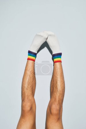Foto de Mínima toma de hombre joven con calcetines con símbolos de arco iris pies arriba - Imagen libre de derechos