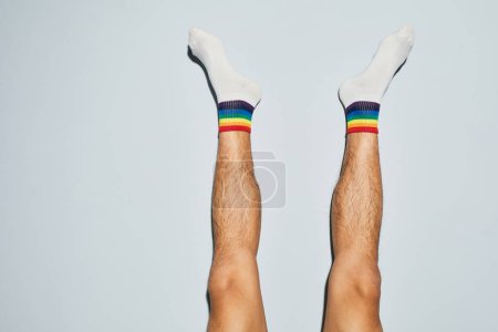 Foto de Mínima toma de hombre joven con calcetines con símbolos de arco iris pies hacia arriba, espacio de copia - Imagen libre de derechos