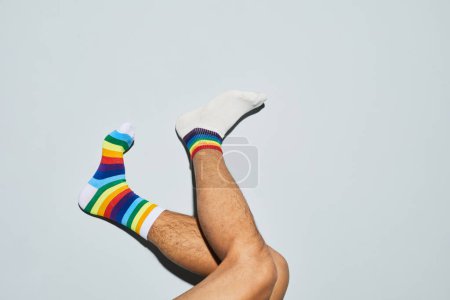 Téléchargez les photos : Plan minimal de l'homme ludique portant des chaussettes inégalées avec des symboles arc-en-ciel pieds vers le haut, espace de copie - en image libre de droit
