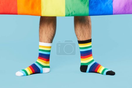 Foto de Mínima toma de pareja con calcetines arcoíris con bandera LGBTQ sobre fondo azul pastel, espacio para copiar - Imagen libre de derechos