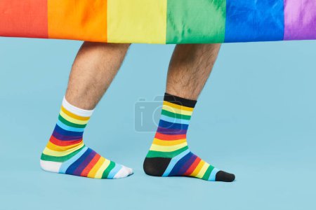 Téléchargez les photos : Gros plan du couple portant des chaussettes arc-en-ciel avec drapeau LGBTQ sur fond bleu pastel - en image libre de droit