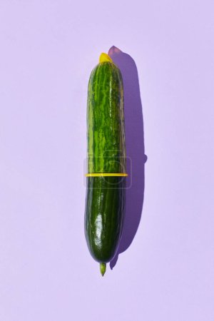 Minimale Aufnahme einer einzelnen Gurke mit Kondom auf pastellfarbenem Hintergrund Safe Sex und Schutzkonzept