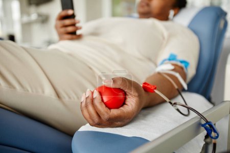 Foto de Primer plano de la joven mujer negra apretando la bola de estrés mientras donaba sangre en el centro de donación, espacio para copiar - Imagen libre de derechos