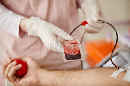 Téléchargez les photos : Gros plan de l'infirmière ajustant le sac de sang du donneur masculin au centre de don de sang ou à l'hôpital, espace de copie - en image libre de droit