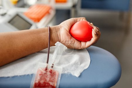Foto de Primer plano de una joven irreconocible donando sangre y sosteniendo una bola roja, espacio para copiar - Imagen libre de derechos