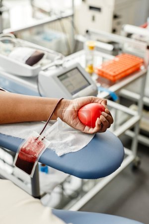 Téléchargez les photos : Gros plan d'une jeune femme méconnaissable faisant don de sang et tenant un espace de copie de cœur rouge - en image libre de droit