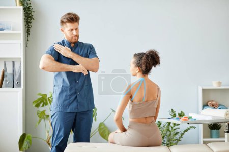 Photo for Portrait of male rehabilitation therapist explaining physio tape technique to young woman, copy space - Royalty Free Image