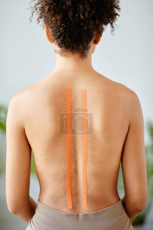 Photo for Vertical portrait of young woman with physio tape on nude back in rehabilitation clinic - Royalty Free Image