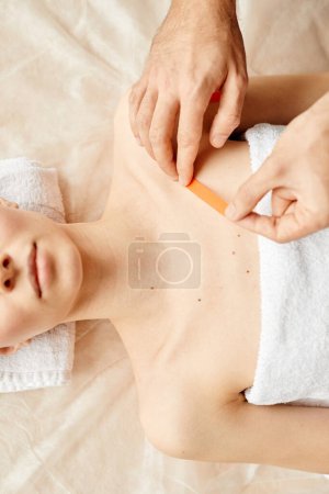 Photo for Top view of rehabilitation specialist putting physio tape on shoulder of young woman during therapy session for joints and muscles - Royalty Free Image