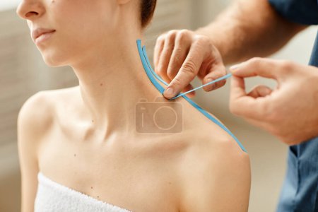 Photo for Close up of rehabilitation specialist putting physio tape on shoulder of young woman during therapy session - Royalty Free Image