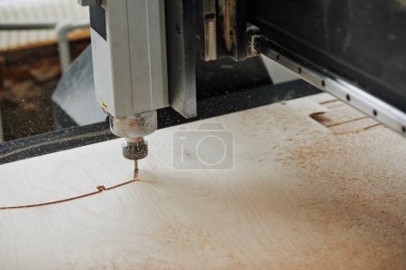 Téléchargez les photos : Gros plan de la machine de gravure CNC découpe du bois dans un atelier de production automatisé avec des flocons de sciure de bois dans l'air, espace de copie - en image libre de droit