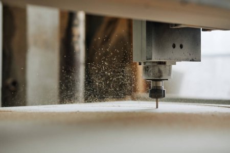 Foto de Macro shot de máquina de grabado CNC de corte de madera en taller de producción automatizado con aserrín escamas en el aire, espacio de copia - Imagen libre de derechos