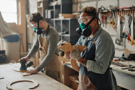 Foto de Retrato vista lateral de dos carpinteros en equipo protector trabajando con madera mientras se construyen muebles de artesanía en taller - Imagen libre de derechos