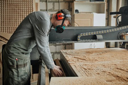 Foto de Retrato de vista lateral del trabajador masculino que usa equipo de protección completo mientras opera máquinas en la producción de madera - Imagen libre de derechos