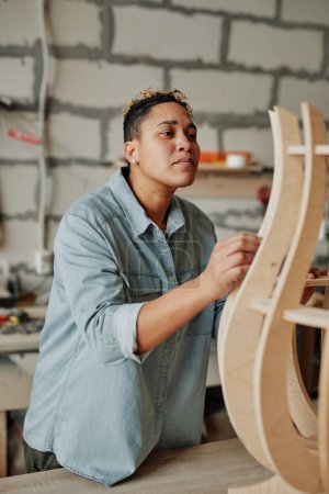Téléchargez les photos : Portrait vertical d'une menuisière moderne concevant un meuble en bois à l'intérieur de l'atelier - en image libre de droit