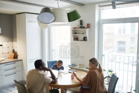 Téléchargez les photos : Scène grand angle sur la famille multiethnique à table dans la cuisine, espace de copie - en image libre de droit