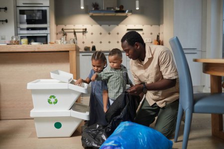Photo for Portrait of caring black father with two kids sorting plastic waste in home kitchen, copy space - Royalty Free Image