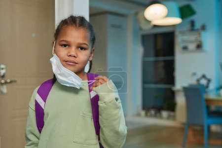 Photo for Front view portrait of African American girl wearing mask and backpack going back to school in September, copy space - Royalty Free Image