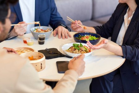 Téléchargez les photos : Gros plan des gens d'affaires profitant de la nourriture asiatique pendant le déjeuner d'affaires au café - en image libre de droit