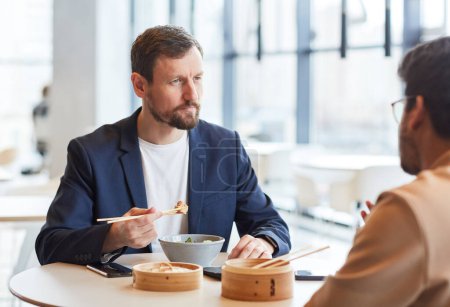 Photo for Portrait of bearded businessman enjoying Asian food during business lunch with colleague at shopping mall cafe - Royalty Free Image