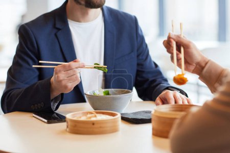 Téléchargez les photos : Homme appréciant la nourriture asiatique pendant le déjeuner d'affaires avec un collègue au centre commercial café, gros plan - en image libre de droit