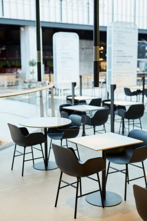 Téléchargez les photos : Image de fond minimale de l'intérieur minimal de la cour alimentaire en noir et blanc avec des tables et des chaises en rangée, espace de copie - en image libre de droit