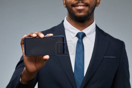 Photo for Closeup of black businessman holding blank smartphone mockup and showing to camera, copy space - Royalty Free Image