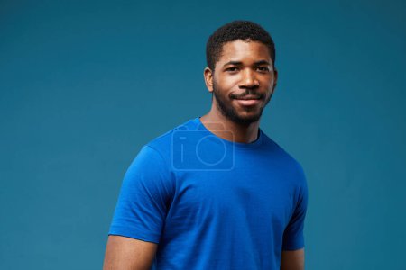 Photo for Portrait of smiling black man wearing blue shirt on vibrant blue background and looking at camera, copy space - Royalty Free Image