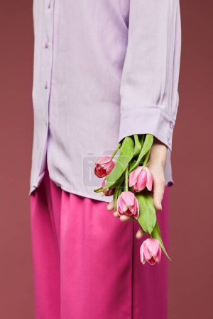 Téléchargez les photos : Gros plan minimal de la jeune femme portant une tenue rose et tenant des tulipes roses douces - en image libre de droit