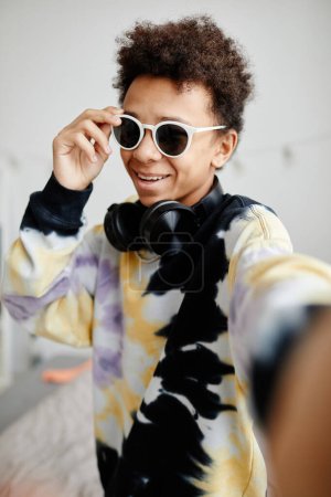 Foto de Vertical POV disparo de moda adolescente negro con gafas de sol y camisa de tinte de corbata mientras posando para foto selfie - Imagen libre de derechos