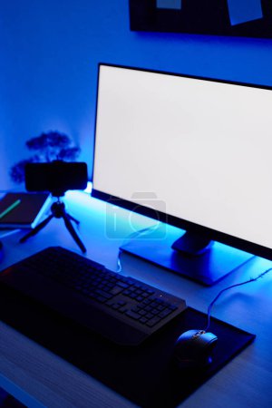 Foto de Imagen de fondo vertical de la configuración del juego PC en el escritorio iluminado con iluminación de neón azul, maqueta de pantalla - Imagen libre de derechos