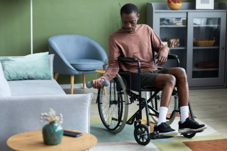 Téléchargez les photos : Portrait complet de jeune homme noir handicapé faisant de l'exercice à la maison à l'aide d'haltère, espace de copie - en image libre de droit