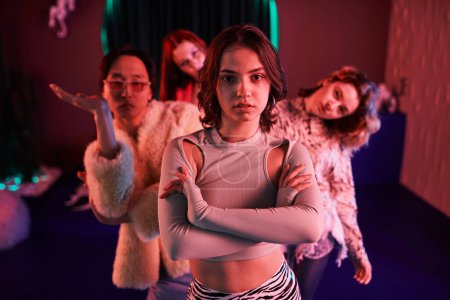 Photo for Waist up portrait of vogue dance crew posing in pink neon light, focus on young girl in foreground - Royalty Free Image