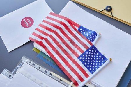 Téléchargez les photos : Image de fond des drapeaux américains avec bulletins de vote sur la table dans le bureau de vote, espace de copie - en image libre de droit