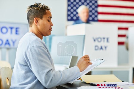 Foto de Retrato de vista lateral de mujer negra adulta llenando papeleta de votación el día de las elecciones, espacio para copiar - Imagen libre de derechos