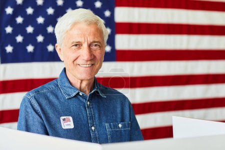 Téléchargez les photos : Portrait d'un homme âgé souriant votant contre fond de bannière des États-Unis, espace de copie - en image libre de droit