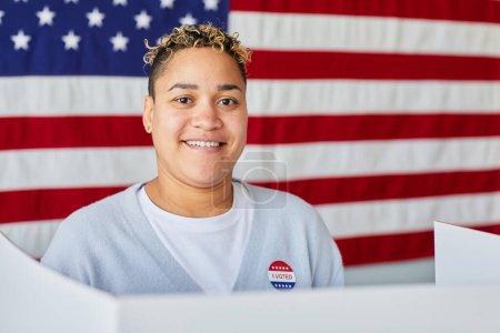 Téléchargez les photos : Portrait de femme noire souriante votant sur fond de drapeau américain, espace de copie - en image libre de droit