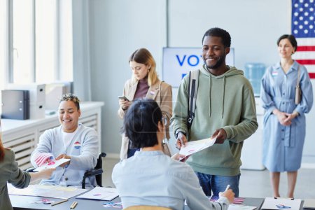 Téléchargez les photos : Divers groupes de personnes votant en ligne et recevant des bulletins de vote se concentrent sur l'homme noir souriant, l'espace de copie - en image libre de droit