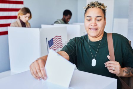 Foto de Retrato de una mujer americana moderna con tatuajes votando y poniendo papeleta en la papelera el día de las elecciones, espacio para copiar - Imagen libre de derechos