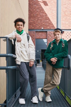 Téléchargez les photos : Portrait de deux amis adolescents multiethniques regardant la caméra debout dans la rue - en image libre de droit