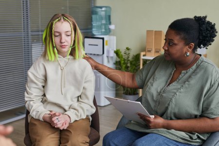 Foto de Chica adolescente sentada en la silla y hablando con un especialista que le da un consejo durante la clase de terapia - Imagen libre de derechos