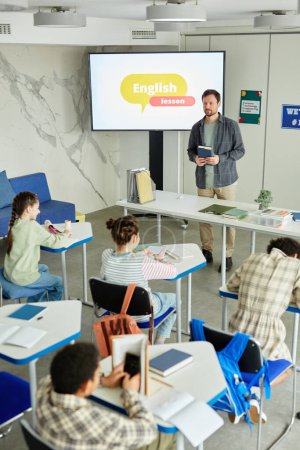 Téléchargez les photos : Portrait vertical d'un groupe diversifié d'enfants qui étudient en classe avec des enseignants masculins pendant les cours d'anglais - en image libre de droit