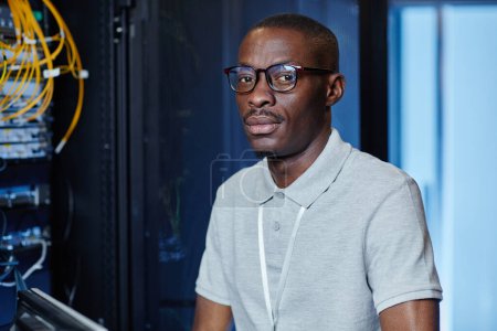 Foto de Retrato del hombre adulto negro trabajando como ingeniero de TI en la sala de servidores y mirando a la cámara, espacio de copia - Imagen libre de derechos