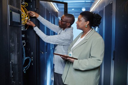 Photo for Waist up portrait of two system managers inspecting server cabinets in data center, copy space - Royalty Free Image