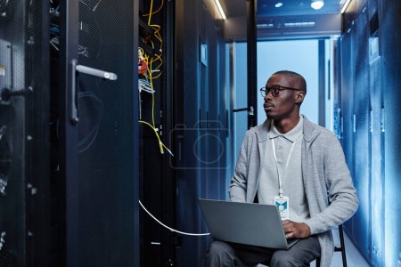 Photo for Portrait of black IT engineer setting up server network and using laptop in data center, copy space - Royalty Free Image