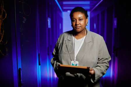 Photo for Waist up portrait of female network engineer holding tablet in server room and looking at camera - Royalty Free Image
