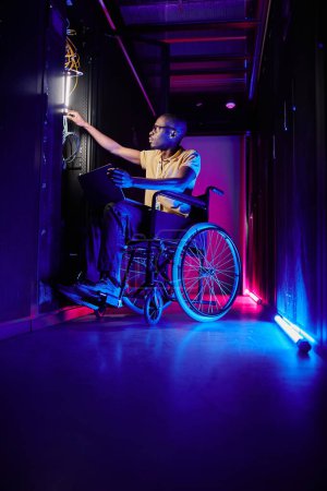 Photo for Full length portrait of person with disability working at system administrator in server room lit by neon light - Royalty Free Image